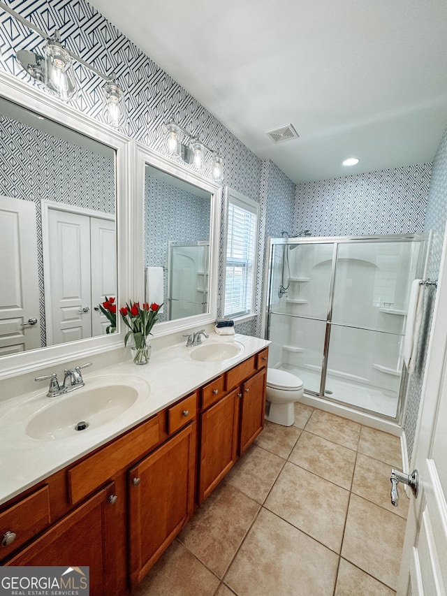 full bath featuring double vanity, wallpapered walls, a stall shower, tile patterned floors, and a sink