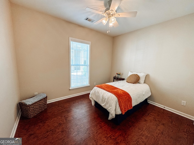 bedroom featuring a ceiling fan, wood finished floors, visible vents, and baseboards