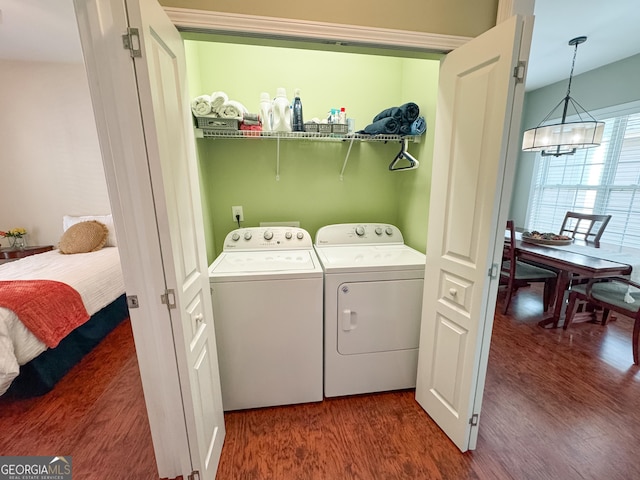 washroom with laundry area, washer and clothes dryer, wood finished floors, and a notable chandelier