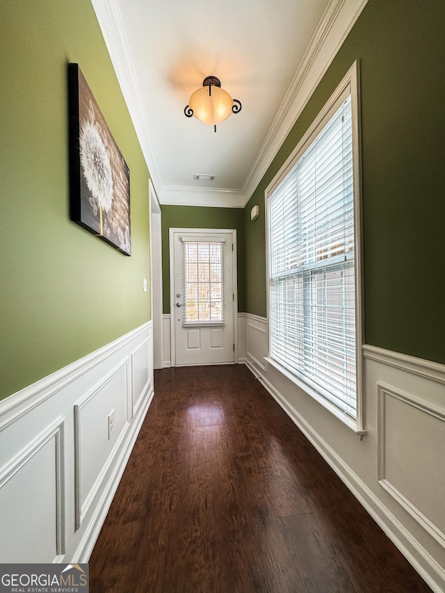 doorway featuring a wainscoted wall, crown molding, visible vents, and wood finished floors