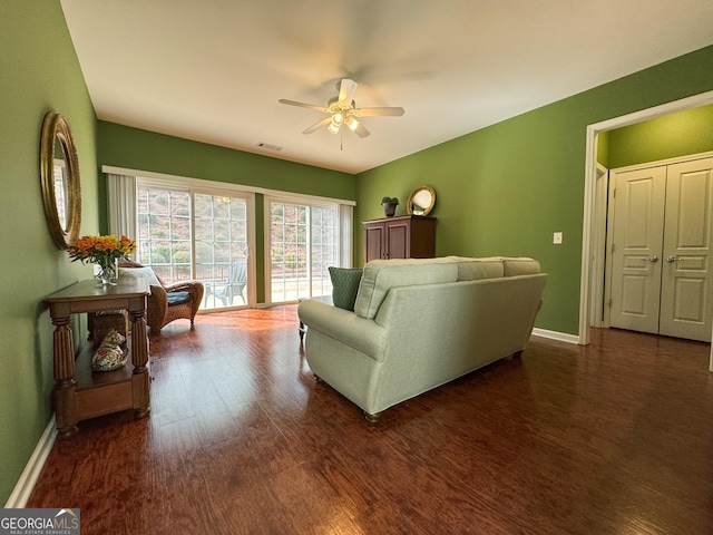 living room featuring baseboards, visible vents, dark wood finished floors, and a ceiling fan