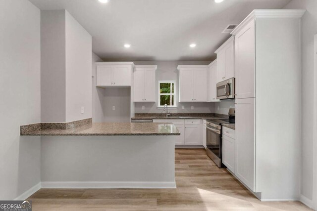 65 Patterson Dr, Franklin, GA 30217 - kitchen with stainless steel appliances, dark stone countertops, white cabinets, a peninsula, and recessed lighting