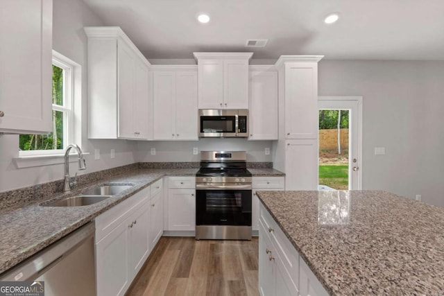 kitchen featuring sink, stainless steel appliances, light stone countertops, light hardwood / wood-style floors, and white cabinets