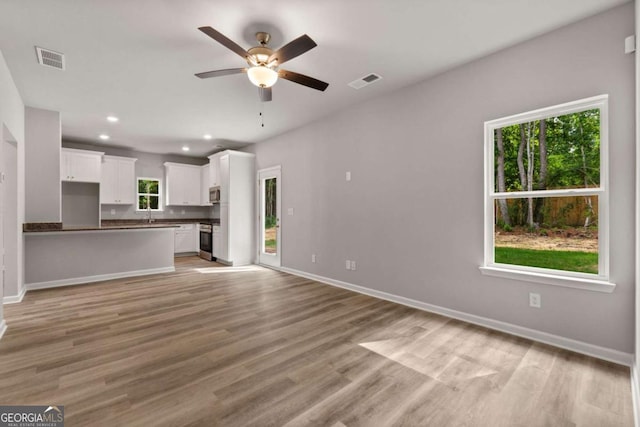 unfurnished living room featuring ceiling fan and light wood-type flooring