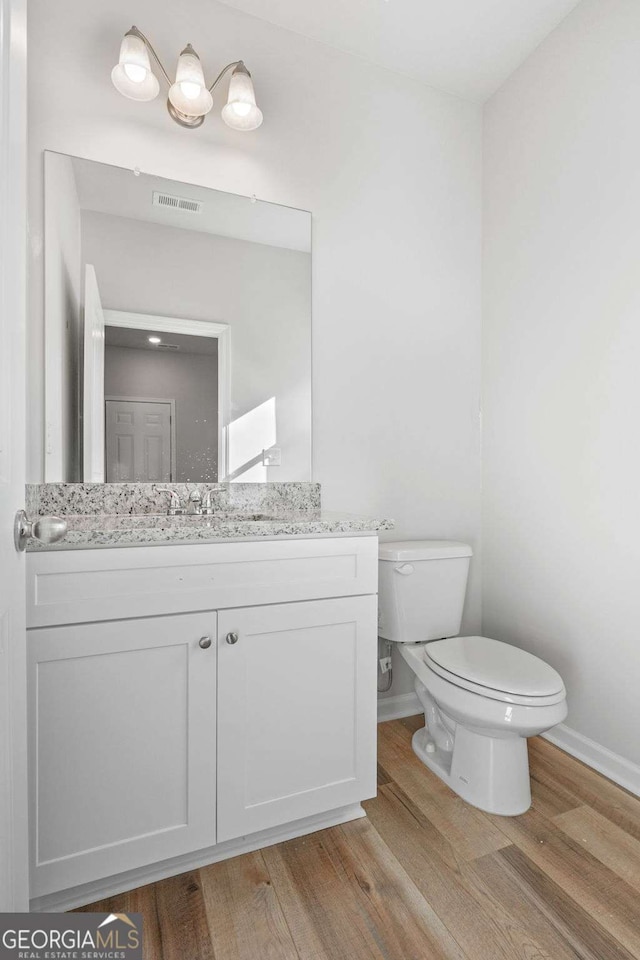 bathroom featuring wood-type flooring, toilet, and vanity