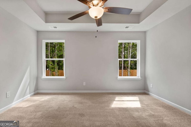 unfurnished room featuring light colored carpet, a raised ceiling, and ceiling fan