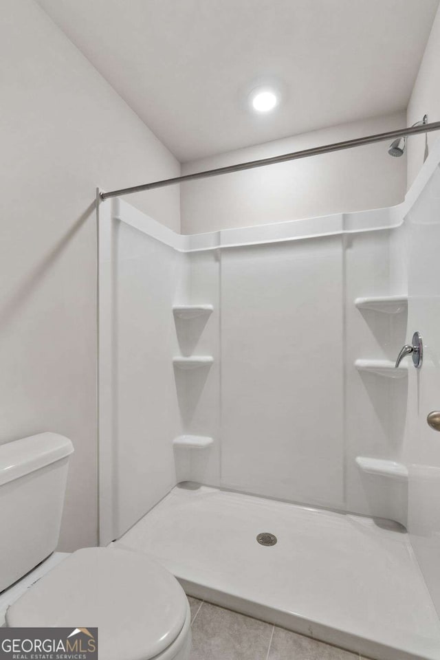 bathroom featuring walk in shower, toilet, and tile patterned flooring