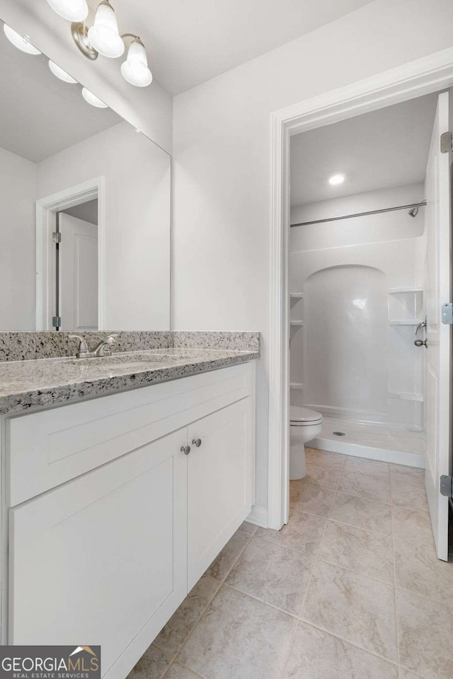 bathroom with vanity, tile patterned floors, toilet, and walk in shower