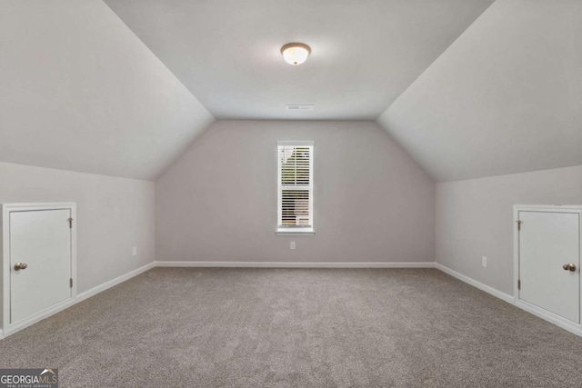 additional living space featuring light carpet and vaulted ceiling