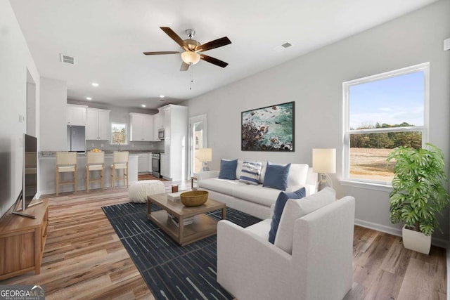 living room featuring ceiling fan, a healthy amount of sunlight, and light wood-type flooring