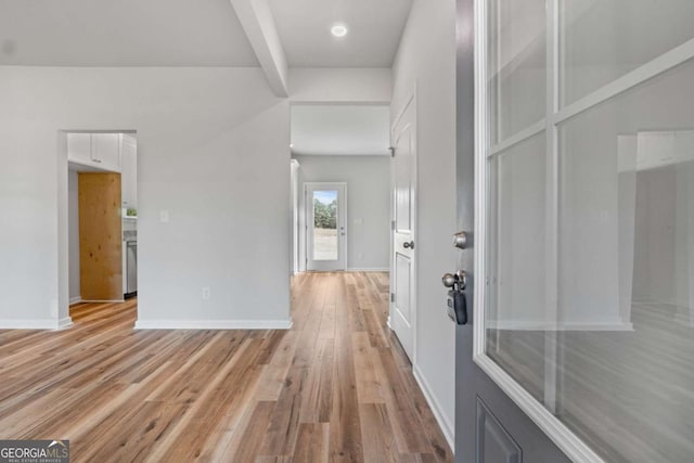 hall with beamed ceiling and light wood-type flooring