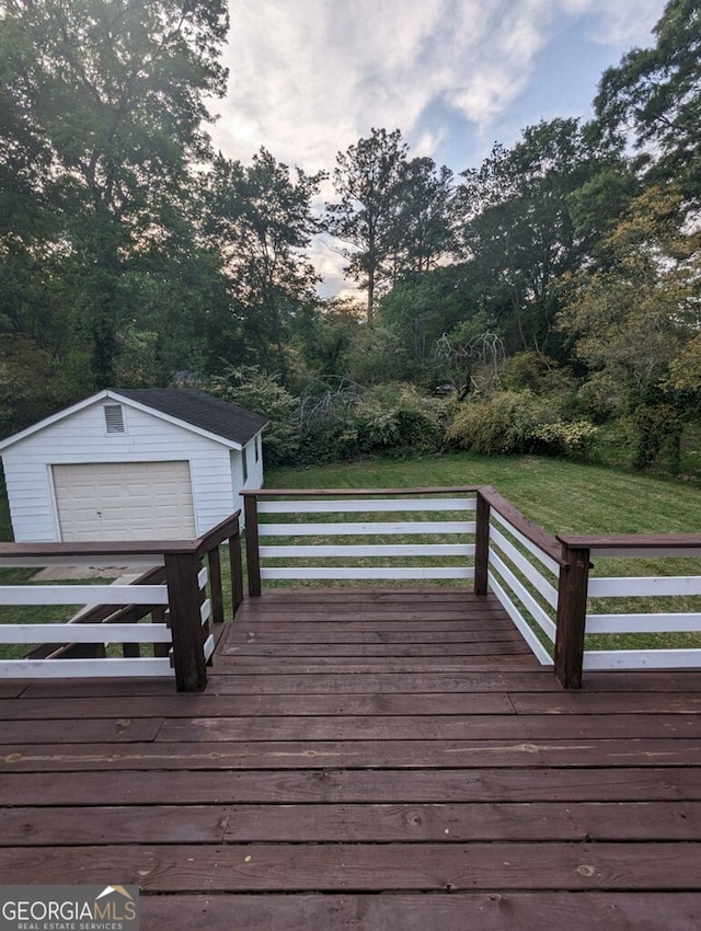 deck at dusk featuring a garage, a yard, an outdoor structure, and a water view