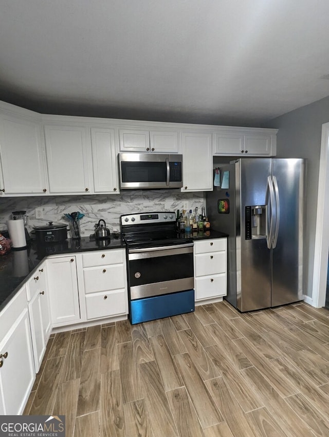 kitchen featuring white cabinetry, light wood-type flooring, tasteful backsplash, and appliances with stainless steel finishes