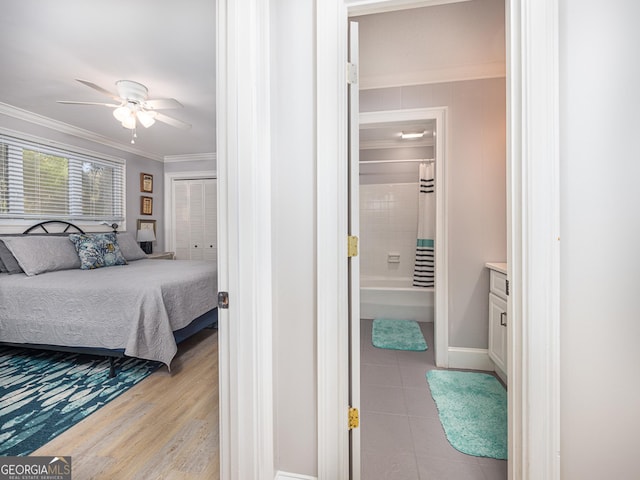 bedroom featuring ensuite bathroom, ceiling fan, light hardwood / wood-style floors, crown molding, and a closet