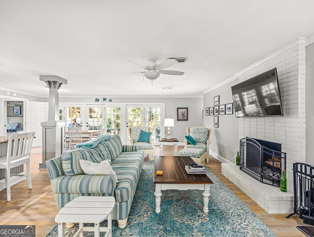 living room with light hardwood / wood-style flooring, a fireplace, ornamental molding, and ceiling fan