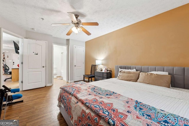 bedroom featuring connected bathroom, wood-type flooring, a textured ceiling, and ceiling fan