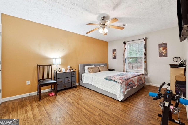 bedroom with ceiling fan, hardwood / wood-style flooring, and a textured ceiling