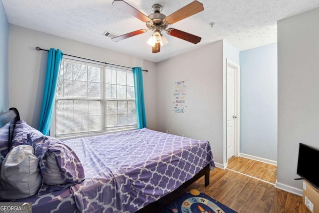 bedroom with ceiling fan, wood-type flooring, and a textured ceiling