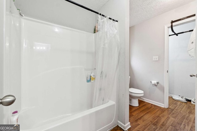 bathroom featuring shower / tub combo with curtain, toilet, hardwood / wood-style floors, and a textured ceiling