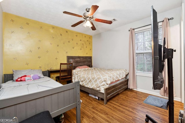 bedroom featuring ceiling fan, hardwood / wood-style floors, and a textured ceiling