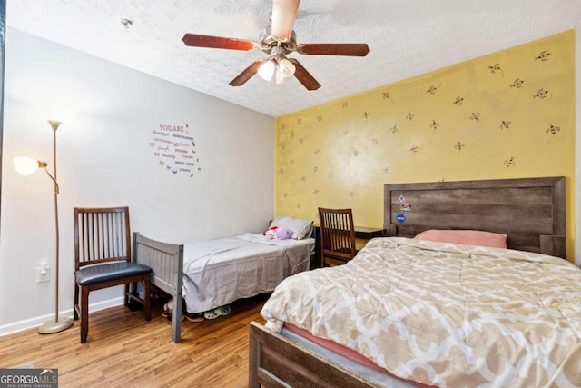 bedroom with hardwood / wood-style flooring, ceiling fan, and a textured ceiling