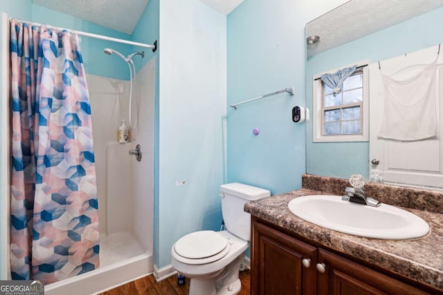 bathroom with vanity, curtained shower, a textured ceiling, and toilet