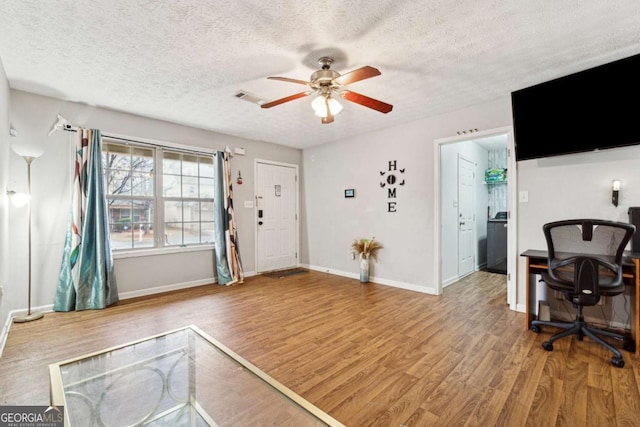 living room featuring ceiling fan, hardwood / wood-style flooring, and a textured ceiling