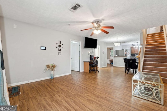 living room featuring hardwood / wood-style flooring, ceiling fan, and a textured ceiling