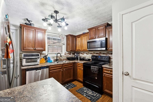 kitchen featuring sink, tasteful backsplash, a textured ceiling, appliances with stainless steel finishes, and light hardwood / wood-style floors