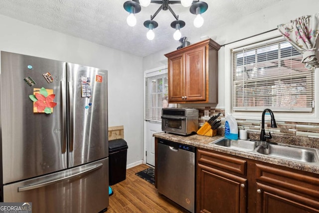 kitchen with sink, wood-type flooring, a textured ceiling, and appliances with stainless steel finishes