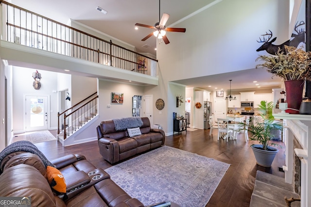 living room with crown molding, ceiling fan, dark wood-type flooring, and a high ceiling