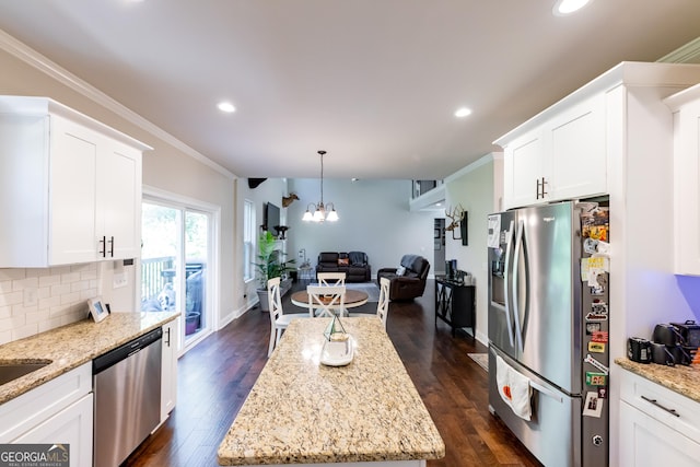 kitchen with light stone countertops, appliances with stainless steel finishes, ornamental molding, and white cabinets