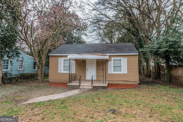 bungalow-style home with fence and a front lawn