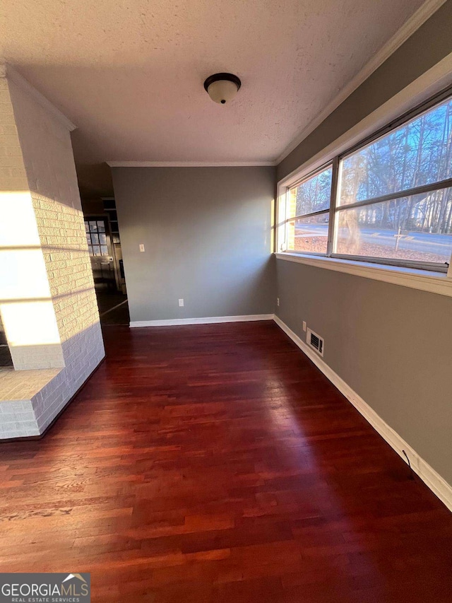 spare room featuring crown molding, dark hardwood / wood-style floors, and a textured ceiling