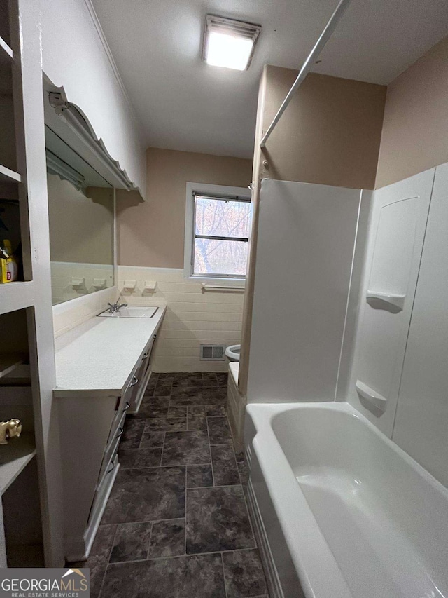 full bathroom featuring vanity, toilet, shower / washtub combination, and tile walls