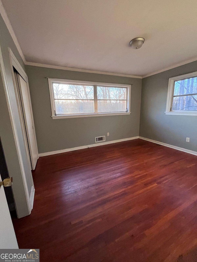 unfurnished bedroom with crown molding, dark hardwood / wood-style flooring, and a closet