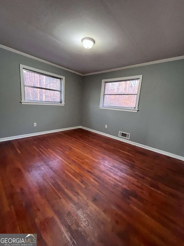 spare room with dark hardwood / wood-style flooring, crown molding, and a healthy amount of sunlight