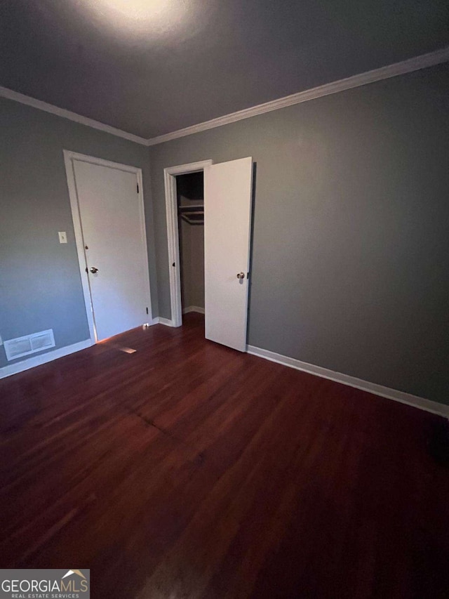 unfurnished bedroom with wood-type flooring, ornamental molding, and a closet