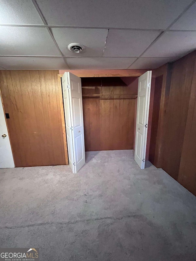 basement with a paneled ceiling and wooden walls