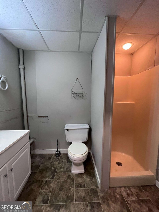 bathroom with walk in shower, a paneled ceiling, vanity, and toilet