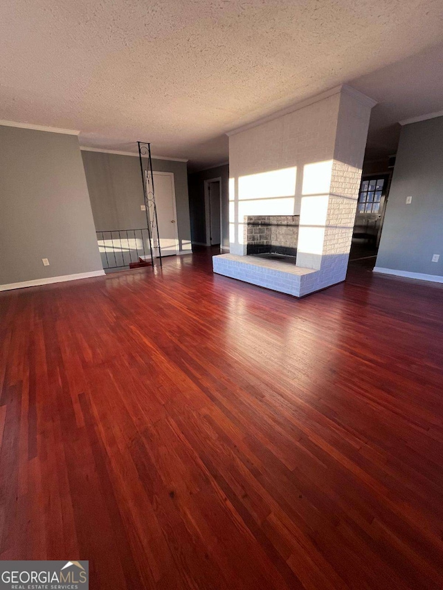 unfurnished living room with dark hardwood / wood-style flooring, a fireplace, ornamental molding, and a textured ceiling