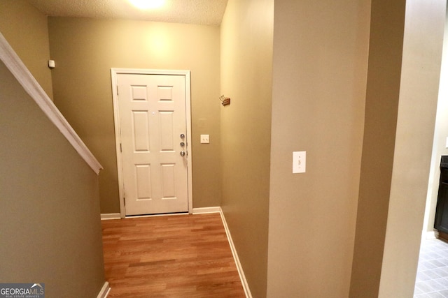 entryway with light hardwood / wood-style floors and a textured ceiling