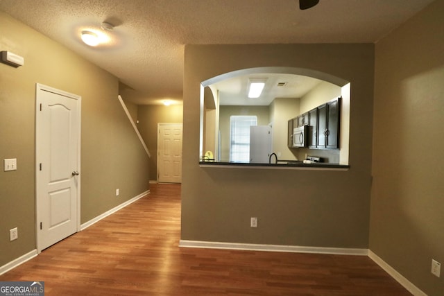 interior space with hardwood / wood-style flooring, kitchen peninsula, white fridge, and a textured ceiling