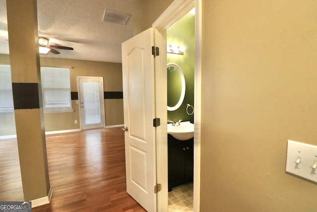 corridor with sink, hardwood / wood-style flooring, and a textured ceiling