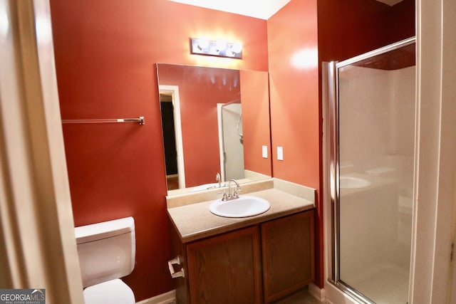 bathroom with vanity, toilet, and a shower with door