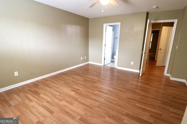 unfurnished bedroom with connected bathroom, light hardwood / wood-style floors, and ceiling fan