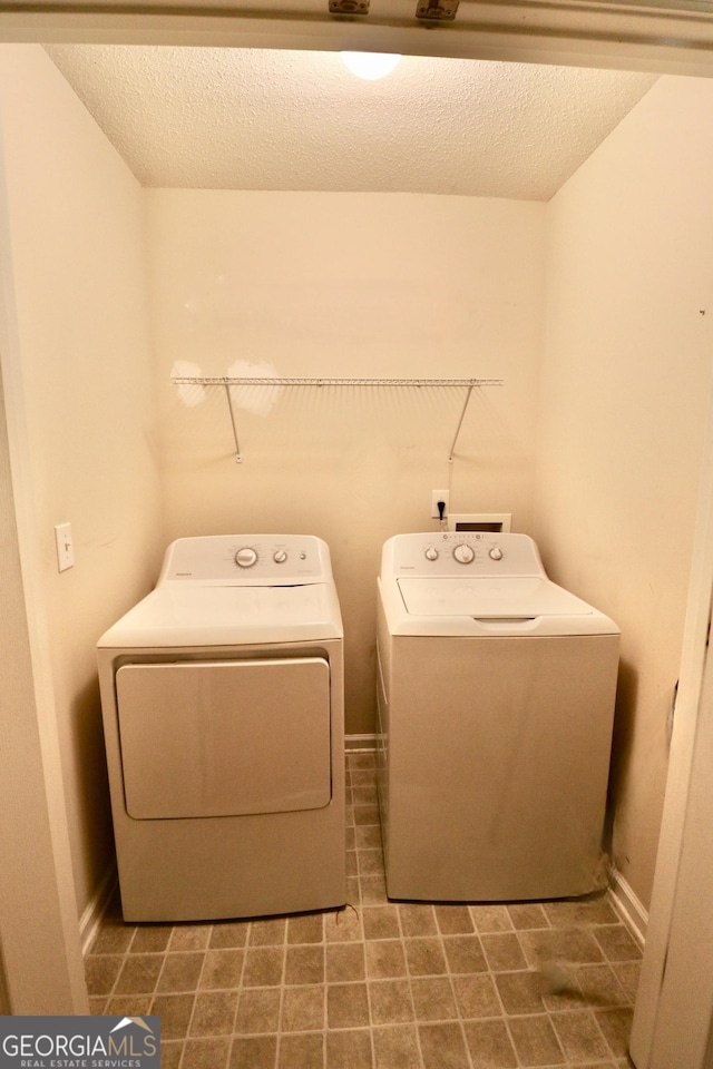 laundry room featuring washer and clothes dryer and a textured ceiling