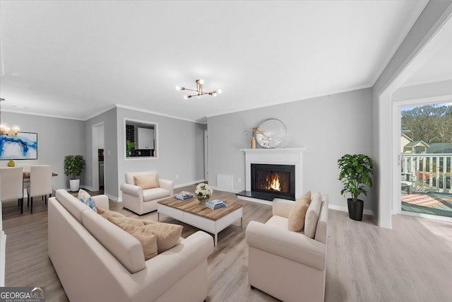 living room with an inviting chandelier, crown molding, and light wood-type flooring