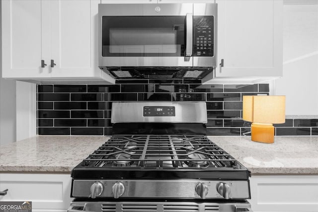 kitchen featuring white cabinetry, stainless steel appliances, and light stone countertops