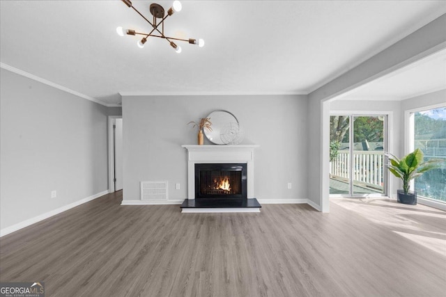 unfurnished living room with wood-type flooring, ornamental molding, and an inviting chandelier